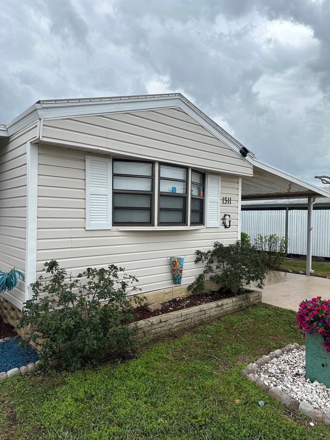 Front view of a modern single-story home with landscaping, under cloudy sky.