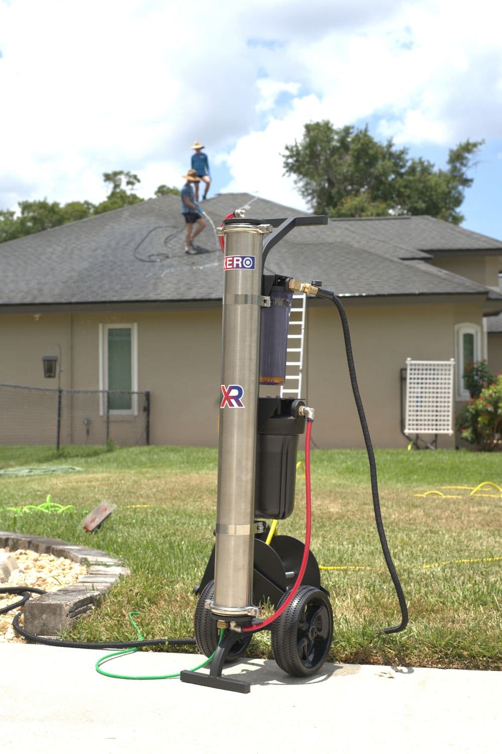 Mobile roof cleaning machine with a user working on a house roof in the background.