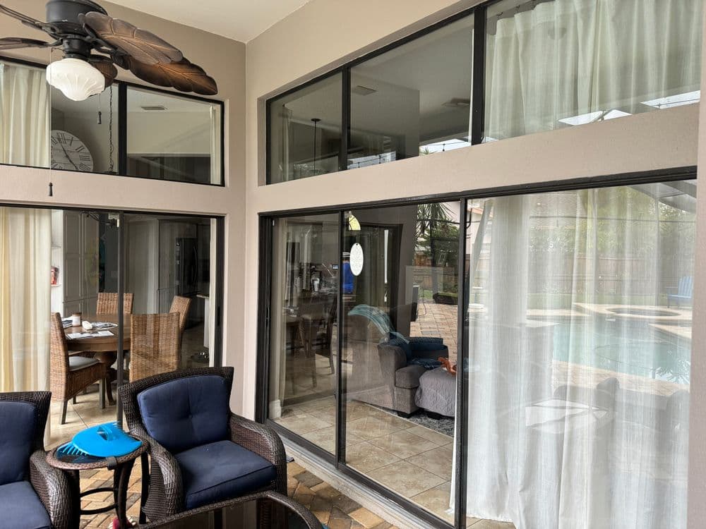 Modern living space featuring large windows, seating area, and a pool view. Natural light emphasizes comfort.