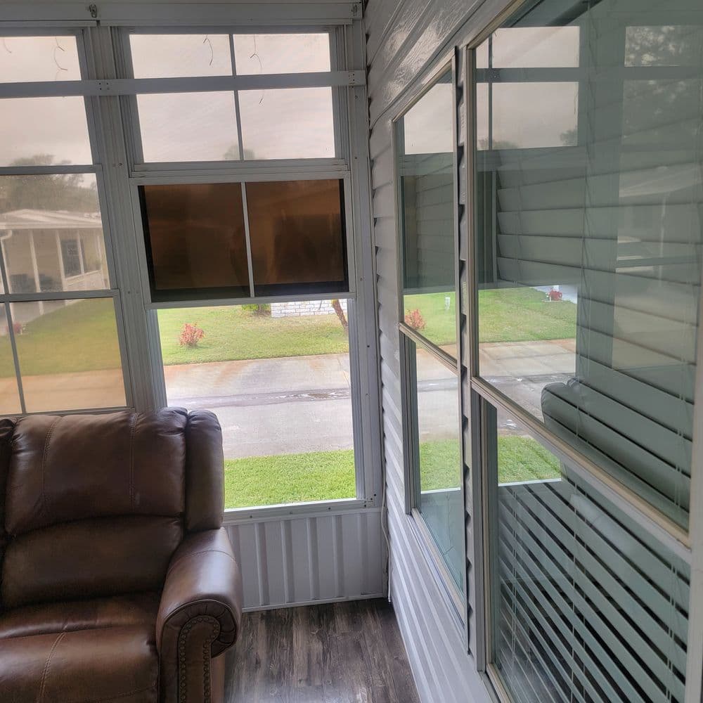 Cozy sunroom with a leather sofa, windows, and outdoor view. Perfect for relaxation.