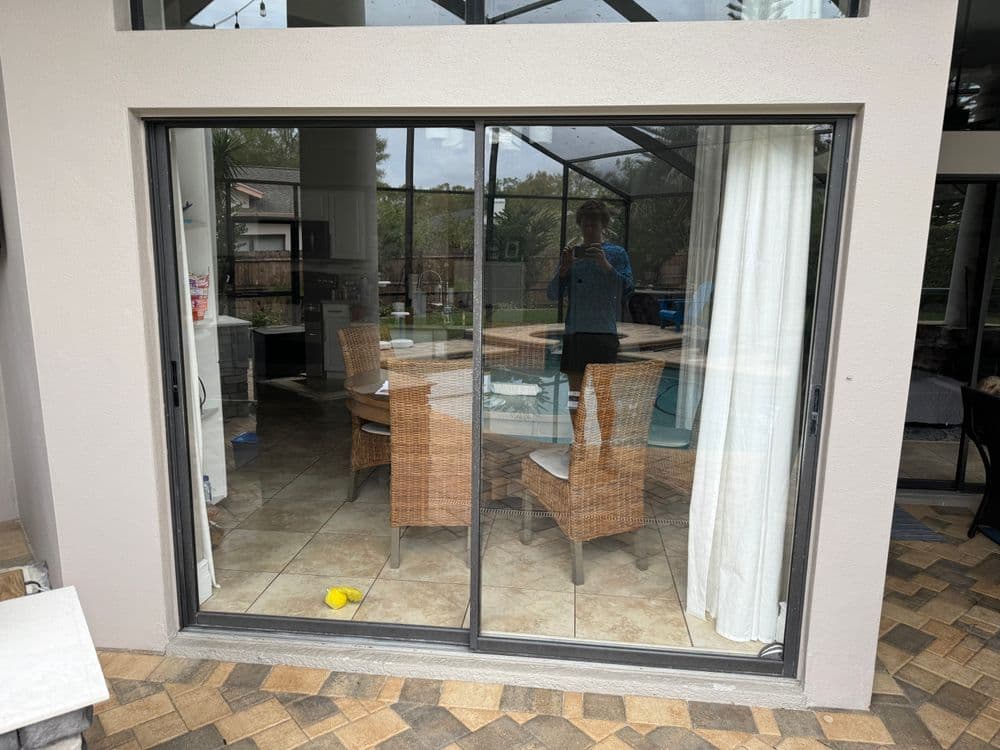 Sliding glass door leading to a dining area with wicker furniture and a view of the pool.