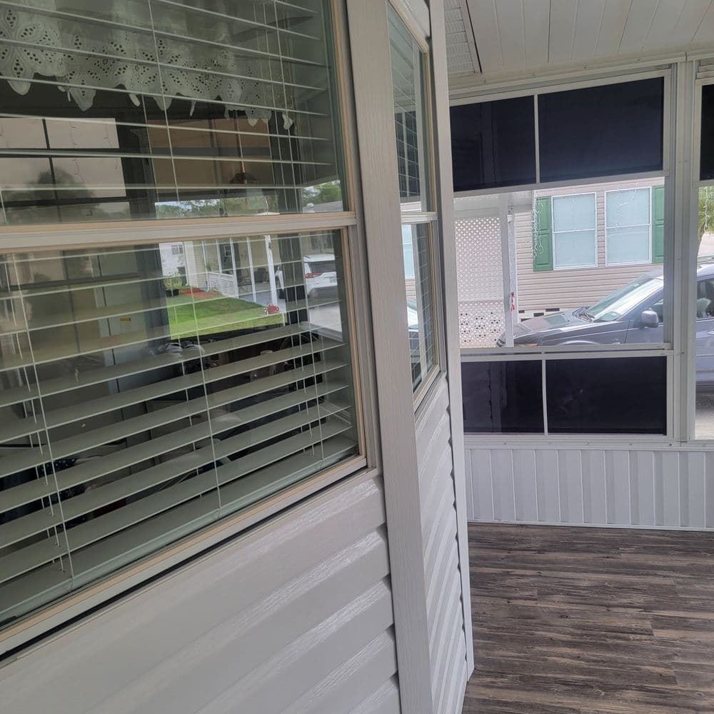 Bright sunroom with white walls, windows, and wooden flooring, showcasing a spacious interior.