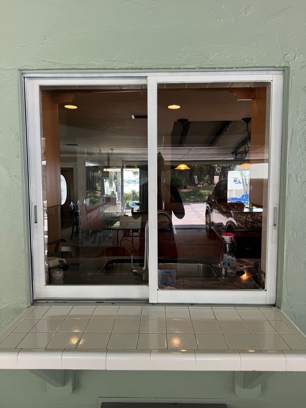 Kitchen pass-through window with a tiled counter, revealing a bright dining area beyond.