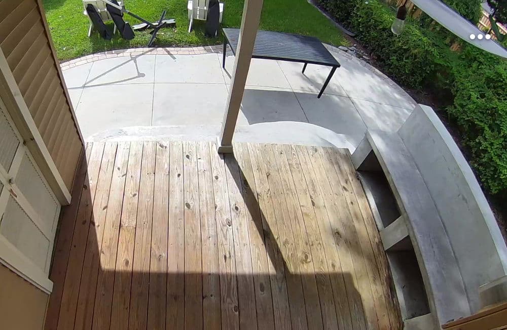 Wooden porch view featuring furniture and green garden landscaping.
