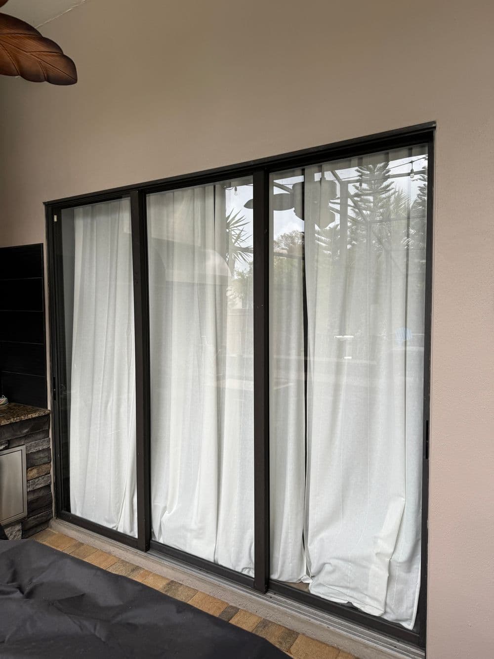 Sliding glass doors with white curtains in a modern indoor setting. Natural light visible outside.